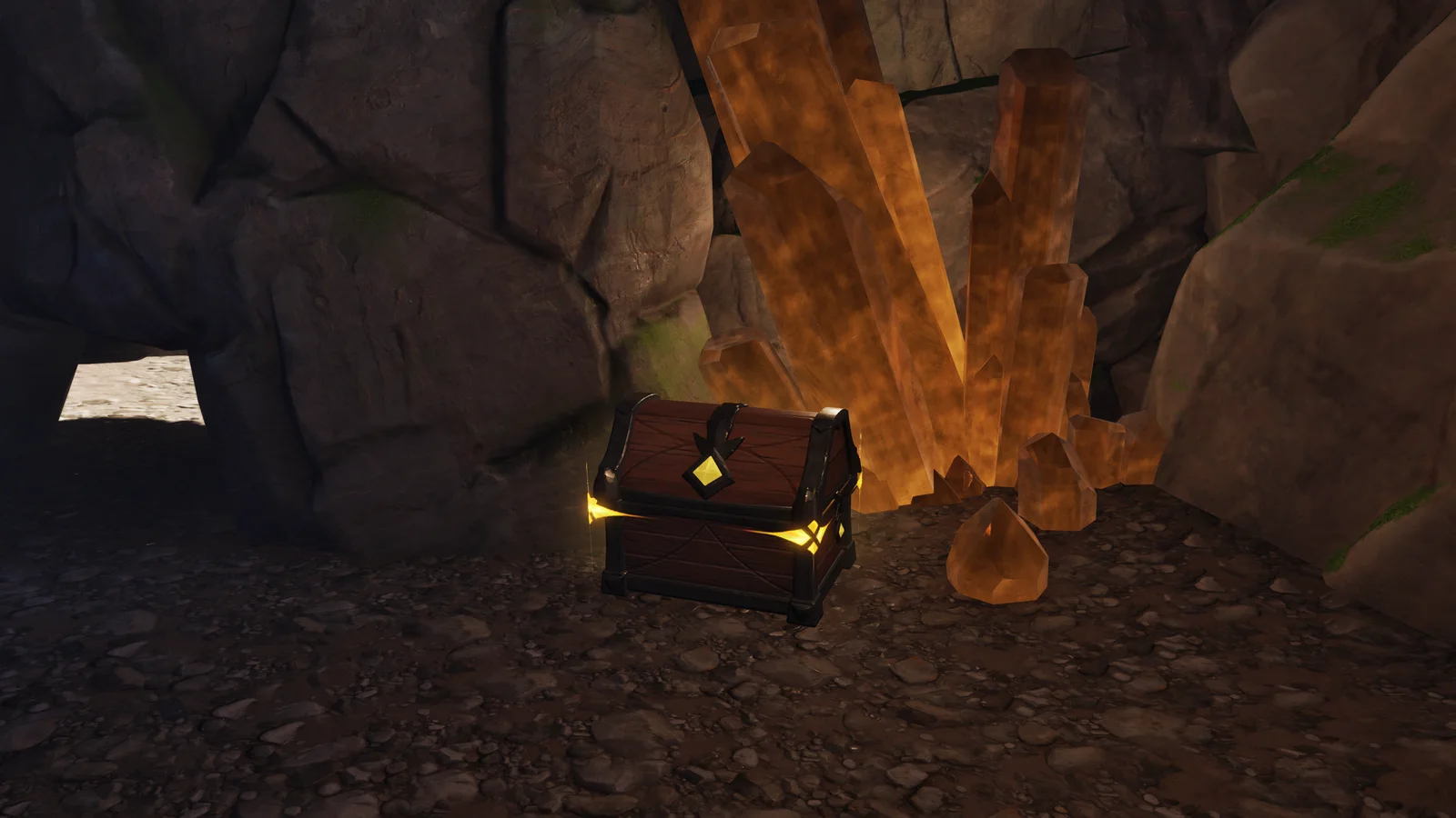 Eine verzierte braune Truhe mit goldenen Beschlägen und leuchtend gelbem Schloss steht in einer Höhle neben großen orangefarbenen Kristallen, links ein Durchgang zum Tageslicht