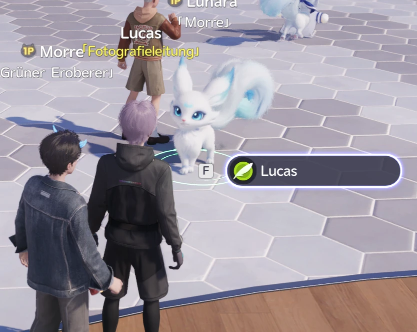 NPC Lucas mit dem Titel Fotografieleitung in Astra: Die Interaktionsanzeige mit F-Taste und Blatt-Symbol steht neben einem weißen Fuchs-Aniimo auf einem Sechseck-Pflaster, zwei Spielfiguren stehen im Vordergrund
